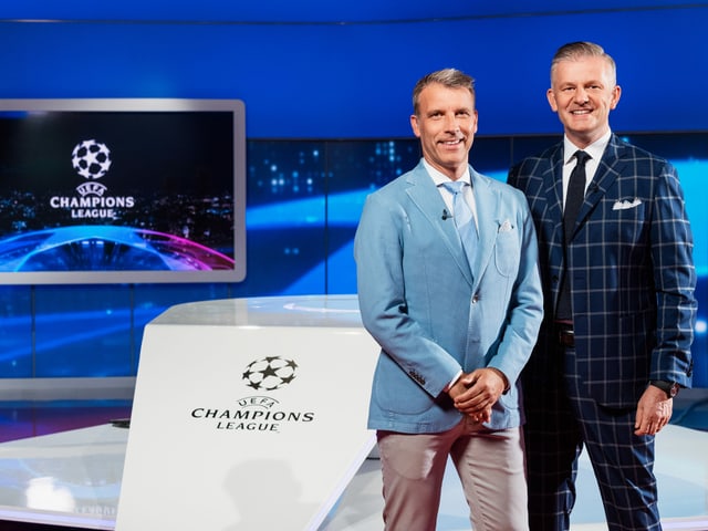 Peter Knäbel und Rainer M. Salzgeber stehen im SRF-Studio vor dem CL-Logo. Peter Knäbel und Rainer M. Salzgeber stehen im SRF-Studio vor dem CL-Logo.