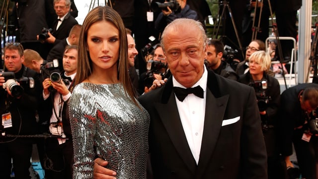 Älterer Mann mit funkelndem Model am Arm Älterer Mann mit funkelndem Model am Arm