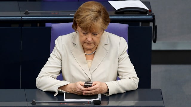 Die deutsche Bundeskanzlerin Angela Merkel mit einem Handy in der Hand Die deutsche Bundeskanzlerin Angela Merkel mit einem Handy in der Hand