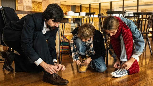 Eine Familie am Boden: alle binden sich die Schuhe. Eine Familie am Boden: alle binden sich die Schuhe.