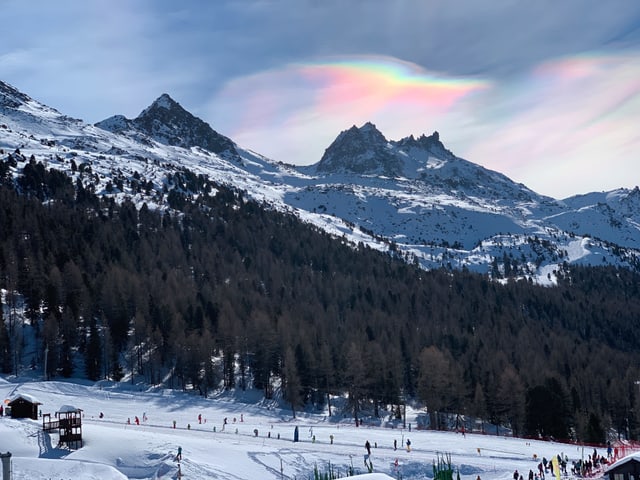 An den Eiskristallen reflektiertes Sonnenlicht lässt die Wolken perlmutfarben schillern.