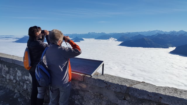 Zwei Frauen geniessen mit Feldstechern die Aussicht über dem Nebelmeer. Zwei Frauen geniessen mit Feldstechern die Aussicht über dem Nebelmeer.