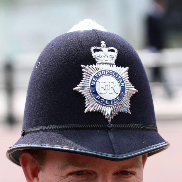 Blick auf einen Helm aus Filz, vorne ein silbernes Kennzeichen mit der Aufschrift "Metropolitan Police". Blick auf einen Helm aus Filz, vorne ein silbernes Kennzeichen mit der Aufschrift "Metropolitan Police".