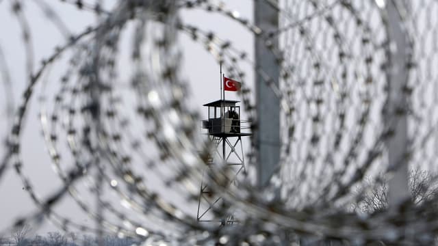 Ein Drahtzaun, im Hintergrund ein Turm mit türkischer Flagge Ein Drahtzaun, im Hintergrund ein Turm mit türkischer Flagge