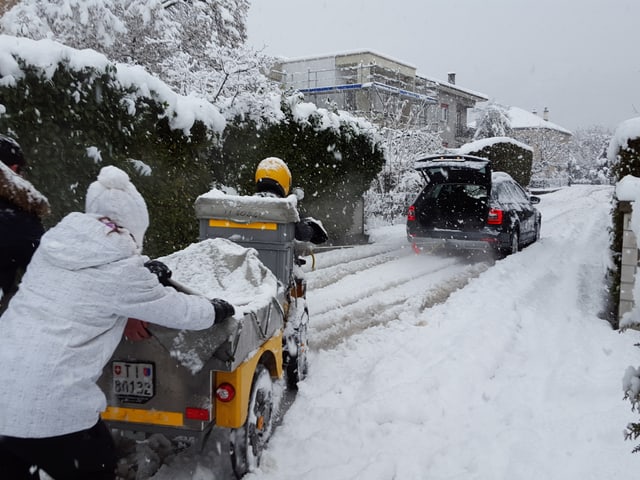 Ein Auto zieht das Dreirad der Pöstlerin aus dem Schnee.