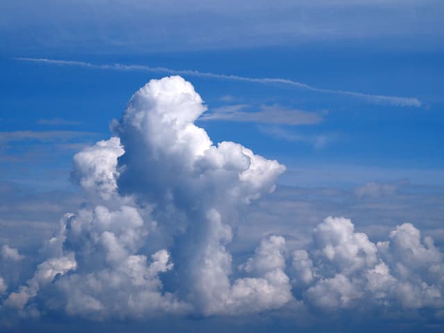 Blauer Himmel, im Vordergrund Wolkentürme, die in den Himmel wachsen wie Bauwerke.