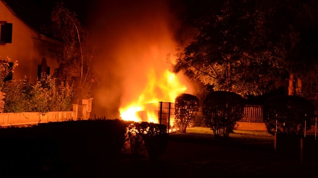 Flammen schiessen in der Nacht in die Luft, daneben Wohnhäuser. Flammen schiessen in der Nacht in die Luft, daneben Wohnhäuser.