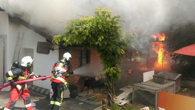 Feuerwehrleute mit Schlauch bekämpfen Feuer Feuerwehrleute mit Schlauch bekämpfen Feuer