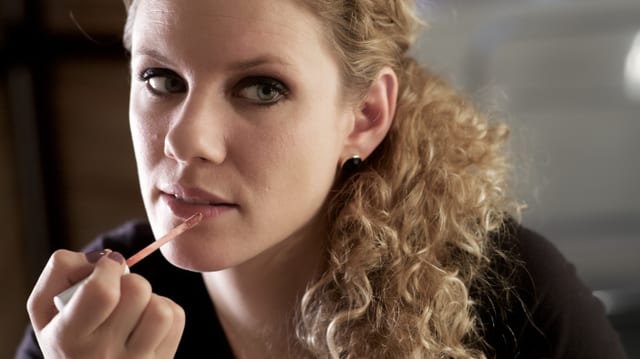 Frau trägt Lipgloss auf. Frau trägt Lipgloss auf.