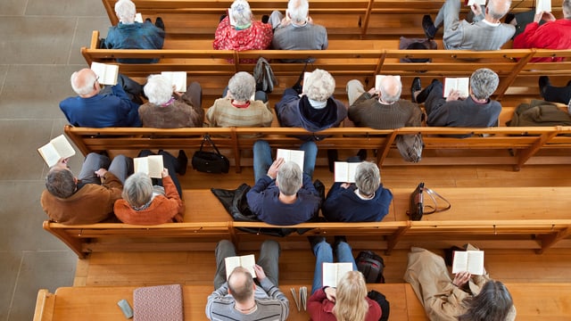Kirchenbank von oben. Vor allem ältere Menschen sitzen in einer Reihe. Kirchenbank von oben. Vor allem ältere Menschen sitzen in einer Reihe.