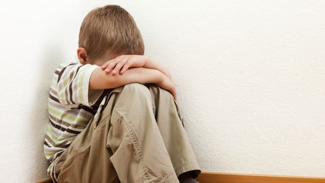 Junge kauert in einer Ecke, die Arme vor dem Gesicht. Junge kauert in einer Ecke, die Arme vor dem Gesicht.