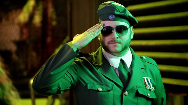 Ein Mann in Uniform und Sonnenbrille salutiert.