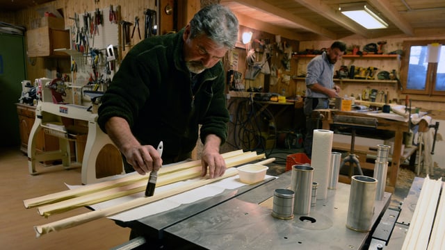 Ein Handwerker bepinselt Holzstäbe. Ein Handwerker bepinselt Holzstäbe.