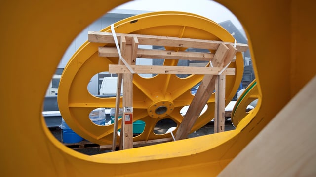 Symbolbild: Ein grosses gelbes Seilbahnrad in der Produktion.