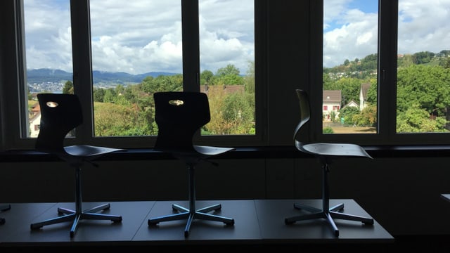 Der Blick auf einen Tisch, auf dem drei Stühle stehen. Dahinter eine grüne Landschaft. Der Blick auf einen Tisch, auf dem drei Stühle stehen. Dahinter eine grüne Landschaft.