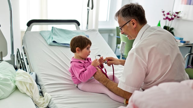 Mann gibt einem Kind ein Stetoskop 