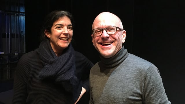 Eine Frau und ein Mann lachen neben einer Theaterbühne in die Kamera. Eine Frau und ein Mann lachen neben einer Theaterbühne in die Kamera.