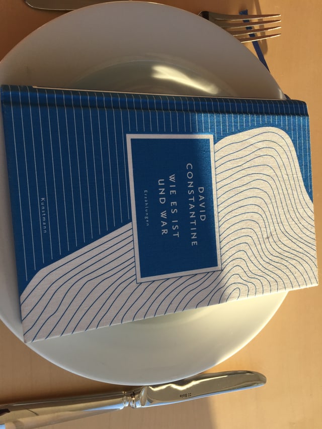 Das Buch «Wie es ist und war» von David Constantine liegt auf einem weissen Teller Das Buch «Wie es ist und war» von David Constantine liegt auf einem weissen Teller