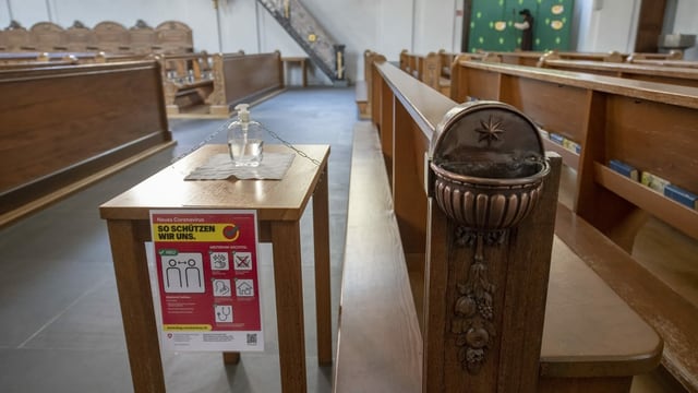 Desinfektionsmittel steht neben dem leeren Weihwasserbecken einer Kirche. Desinfektionsmittel steht neben dem leeren Weihwasserbecken einer Kirche.