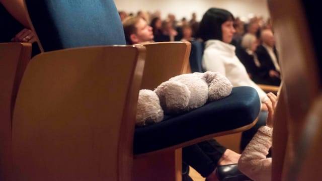 Ein Teddy liegt auf einem Stuhl in einem Konzertsaal. Ein Teddy liegt auf einem Stuhl in einem Konzertsaal.
