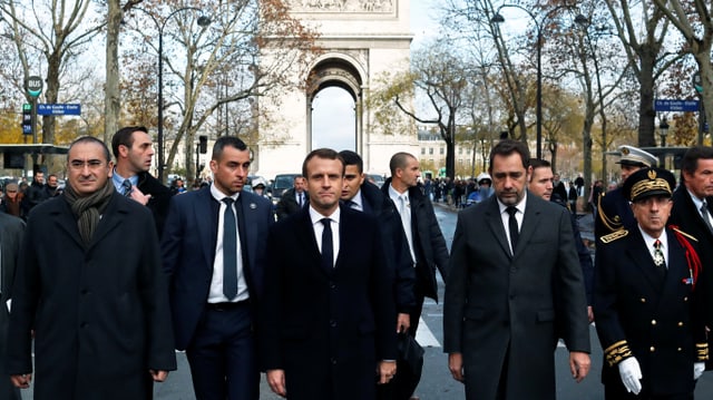 Macron und weitere Männer auf den Champs Elysées, im Hintergrund der Arc de Triopmphe. Macron und weitere Männer auf den Champs Elysées, im Hintergrund der Arc de Triopmphe.