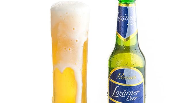 Ein schäumendes Bierglas und daneben steht eine grüne Bierflasche mit blauer Etikette. Ein schäumendes Bierglas und daneben steht eine grüne Bierflasche mit blauer Etikette.