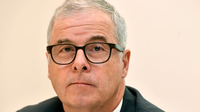 Ein Mann mit grauen Haaren und schwarzer Brille blickt in die Kamera. Ein Mann mit grauen Haaren und schwarzer Brille blickt in die Kamera.