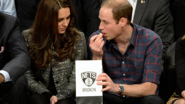 Kate und William sitzend. William hat eine Tüte Popcorn in der Hand. Kate und William sitzend. William hat eine Tüte Popcorn in der Hand.