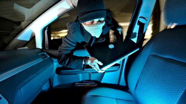 Ein junger Mann bricht in ein Auto ein und entwendet einen Laptop. Ein junger Mann bricht in ein Auto ein und entwendet einen Laptop.