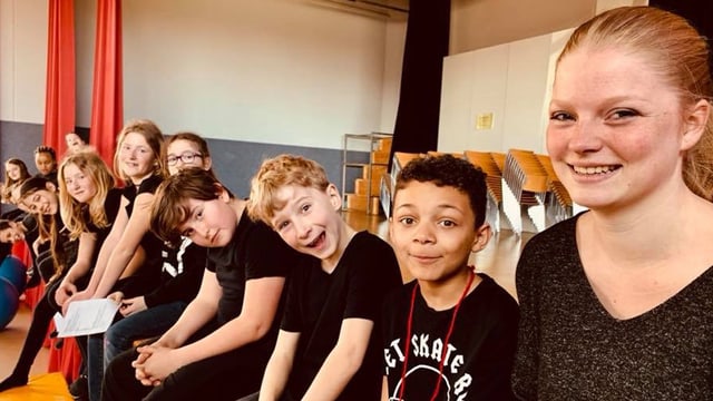 Kinder und Jugendliche sitzen in einer Reihe Kinder und Jugendliche sitzen in einer Reihe