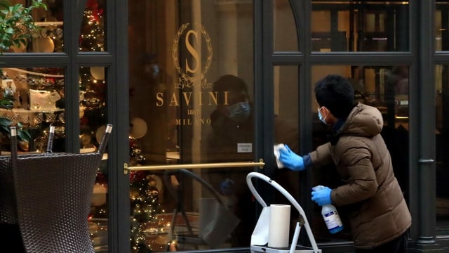 Mann putzt Fensterscheibe vor Restaurant in Italien