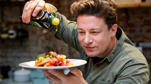 Oliver träufelt Olivenöl über einen angerichteten Teller mit Essen. Oliver träufelt Olivenöl über einen angerichteten Teller mit Essen.
