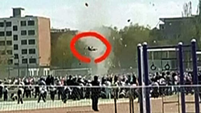 Blick auf den Sportplatz der Schule über dem ein Knabe schwebt Blick auf den Sportplatz der Schule über dem ein Knabe schwebt