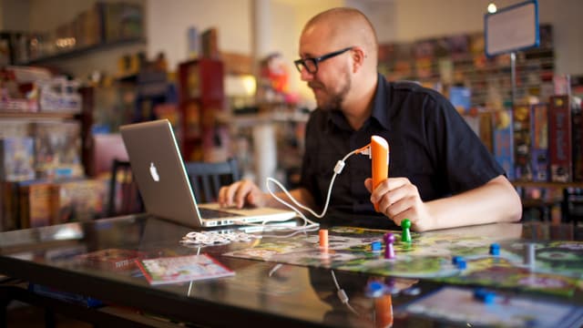 Spieleautor Ulrich Blum testet ein Spiel für die stiftförmige Tiptoi-Konsole vor seinem Notebook. Spieleautor Ulrich Blum testet ein Spiel für die stiftförmige Tiptoi-Konsole vor seinem Notebook.
