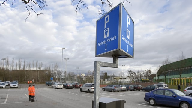 Parkuhr mit Schild "Zentrale Parkuhr" bei grossem Parkplatz Parkuhr mit Schild "Zentrale Parkuhr" bei grossem Parkplatz