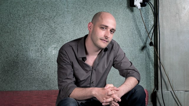 Andreas Schaerer sitzt auf einem Sofa. Andreas Schaerer sitzt auf einem Sofa.