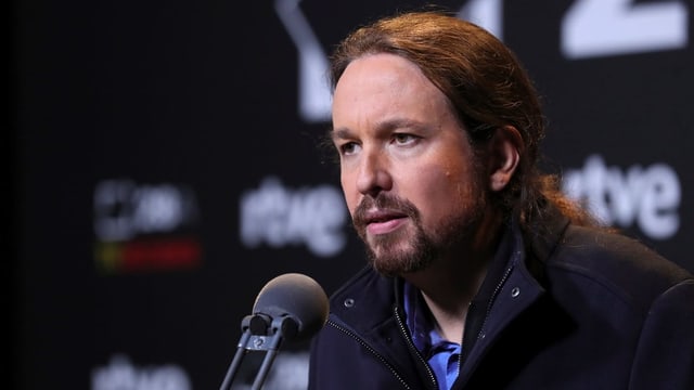Pablo Iglesias mit langen Haaren und schwarzem Pullover bei einer Rede. Pablo Iglesias mit langen Haaren und schwarzem Pullover bei einer Rede.