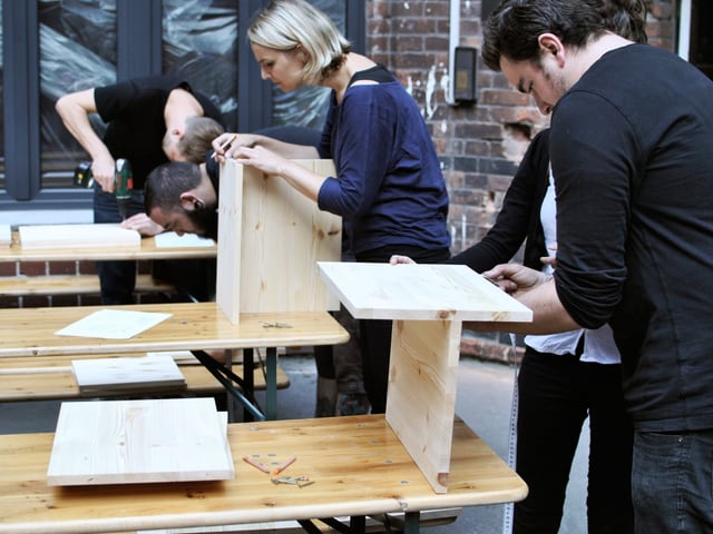 Verschiedene Menschen bauen an einem Möbel. Verschiedene Menschen bauen an einem Möbel.