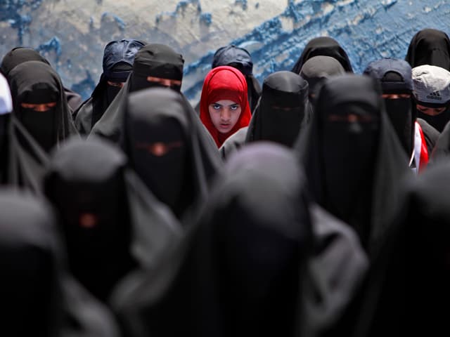 Verschleierte Frauen, in der Mitte ein Mädchen mit rotem Kopftuch. Verschleierte Frauen, in der Mitte ein Mädchen mit rotem Kopftuch.