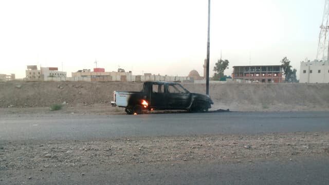 Auf einer Strasse in Tikrit steht ein ausgebranntes Auto Auf einer Strasse in Tikrit steht ein ausgebranntes Auto
