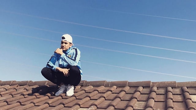 junger Rapper sitzt auf einem Dach junger Rapper sitzt auf einem Dach
