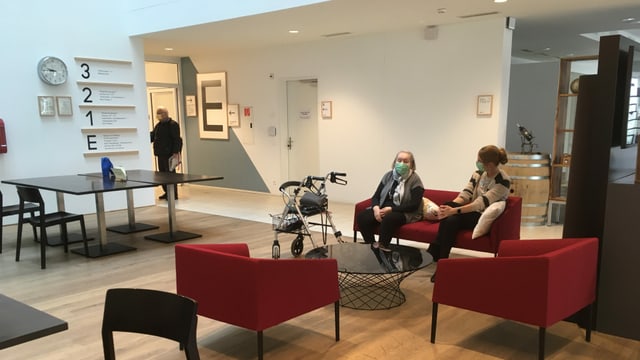 Zwei Frauen sitzen auf einem Sofa in einem Gemeinschaftsraum. Zwei Frauen sitzen auf einem Sofa in einem Gemeinschaftsraum.