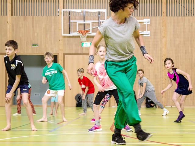 Turnhalle, Lucia Baumgartner tanzt vor, im Hintergrund Kinder, die nachtanzen Turnhalle, Lucia Baumgartner tanzt vor, im Hintergrund Kinder, die nachtanzen