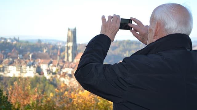 Ein Mann fotografiert mit seinem Smartphone das Panorama einer Stadt. Ein Mann fotografiert mit seinem Smartphone das Panorama einer Stadt.