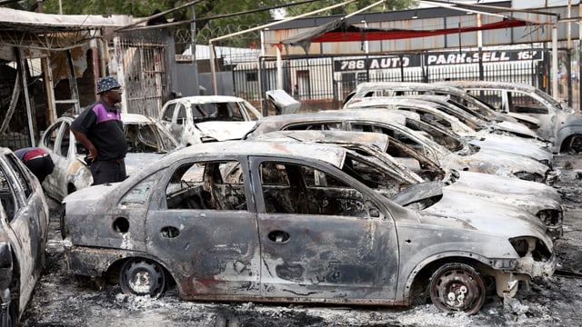 Mann vor verbrannten Autos. Mann vor verbrannten Autos.