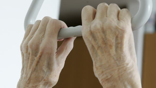 Symbolbild: Zwei Hände eines alten Menschen halten den Griff über dem Spitalbett. Symbolbild: Zwei Hände eines alten Menschen halten den Griff über dem Spitalbett.