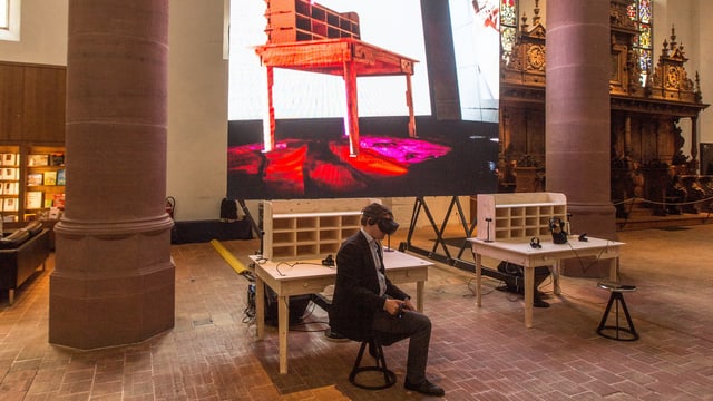 Ein Mann sitzt mit Virtual-Reality-Brille im Museum. Ein Mann sitzt mit Virtual-Reality-Brille im Museum.
