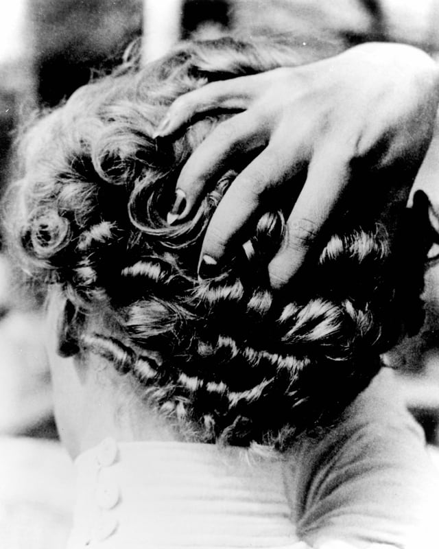 Eine Frau fasst sich mit ihrer Hand an den krausen Hinterkopf. Eine Frau fasst sich mit ihrer Hand an den krausen Hinterkopf.