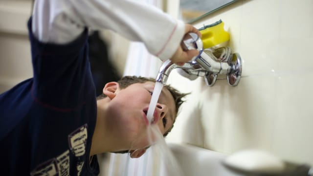 Bub trinkt Wasser aber einem Wasserhahn Bub trinkt Wasser aber einem Wasserhahn