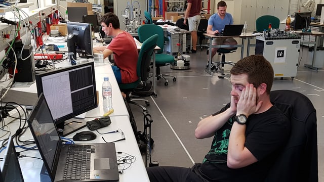 Junge Männer am Computer, einer fasst sich mit beiden Händen an den Kopf. Junge Männer am Computer, einer fasst sich mit beiden Händen an den Kopf.